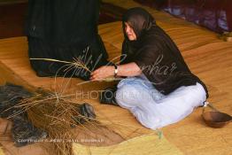 Image du Maroc Professionnelle de  Sous sous une tente bédouine une artisane prépare un sous plat en osier durant le grand Moussem de Tan Tan, classé en 2005 patrimoine immatériel humain mondial de l'Unesco. Le Moussem est une sorte de foire annuelle, à la fois économique, culturelle et sociale. chaque année la majorité des tribus et des grandes familles nomades du désert se retrouvent sur un site désertique "Place de la Tolérance et de la Paix " à la périphérie de Tan Tan où  danse, chants, course de chameaux et fantasia font partie des festivités. , Samedi 18 septembre 2004, ((Photo / Abdeljalil Bounhar) 